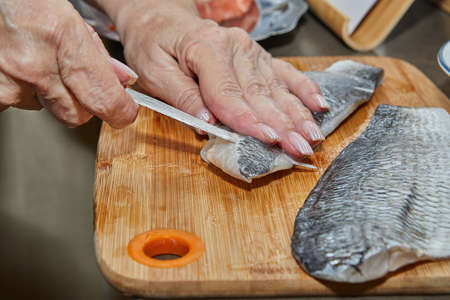 Chef is skinning salmon fillets for cooking.の写真素材