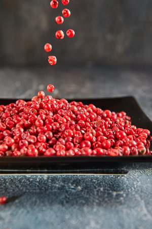 Pour red peppercorns on top of plate of pepper.の写真素材