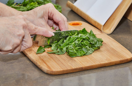 Cook cuts the basil into small pieces on wooden board.の写真素材