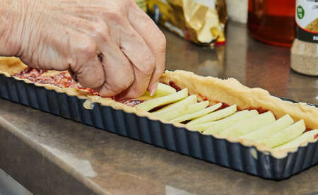Chef prepares apple pie and adds apples to the base of the dough.の写真素材