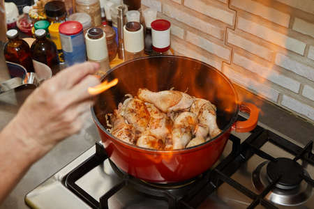 Flamber chicken legs in saucepan on the gas stove.の写真素材