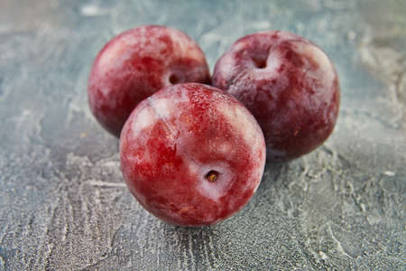 Fresh plums on a blue background. background of beautiful home plumsの写真素材