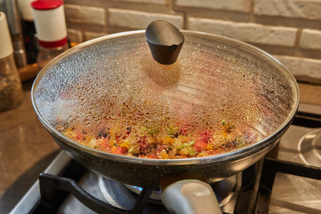Frying pan on gas stove with the texture of drops on a glass lid with selective focus, backgroundの写真素材