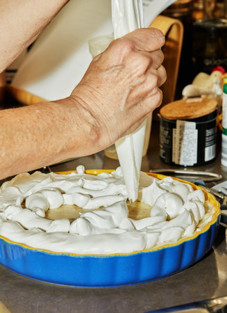 Woman squeezes cream from special bag into banana cake pan in her home kitchen.
