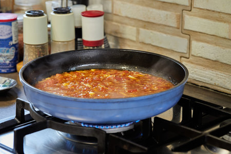 Tomato sauce, mushrooms and capers are fried in pan on gas stove for cooking Veal tongue. French...