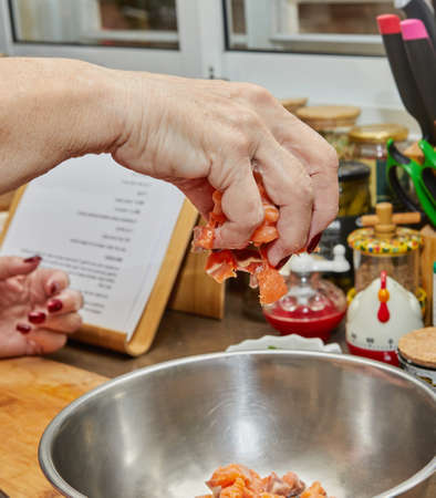 Chef tosses salmon cubes into a bowl to prepare recipe from the internetの写真素材