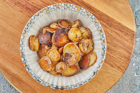 Stir-fried potatoes in a plate on wooden board. flat lay