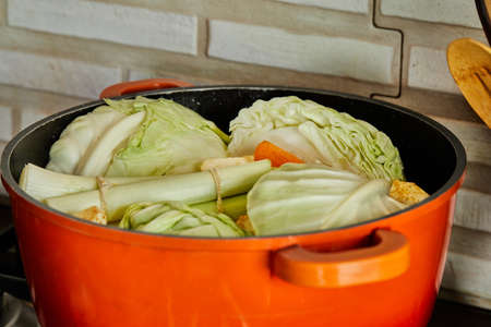 Leek, cabbage, radish, carrots and onions are cooked in pot on gas stove.の写真素材