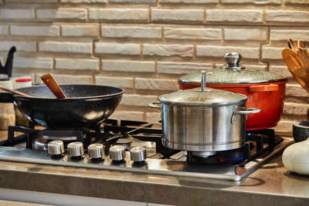 Pots with cooking food in the kitchen on gas stoveの写真素材