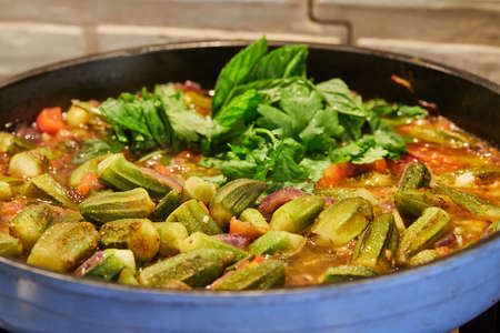 Okra and fried purple onions are pan-fried with cilantro and basil on gas stoveの写真素材