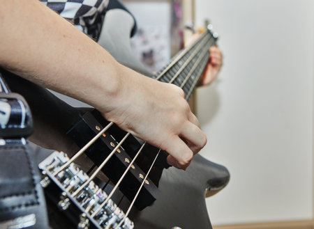 Teenager plays the bass guitar in home music studio