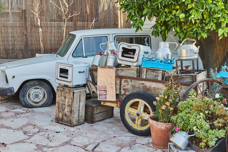 Old car, wheelbarrow with antique utensils made of wood and metal, to decorate the courtyard of the...