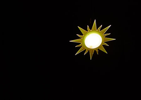 Lamp in the shape of the sun on black backgroundの写真素材