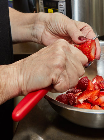 Chef cuts strawberries for dessert in the home kitchen.の写真素材