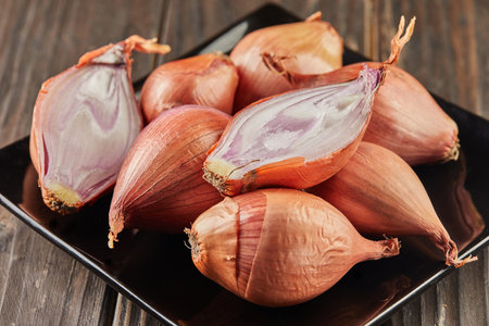 Purple onion lies on black plate on wooden backgroundの写真素材