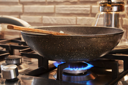 Frying pan on gas stove on fire with dish being prepared.の写真素材