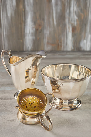 Set of antique silver crockery on gray concrete background