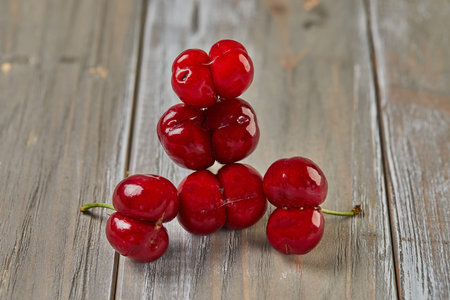 Natures Oddity: ugly, irregularly shaped cherry stands out against a rustic wooden backdropの写真素材