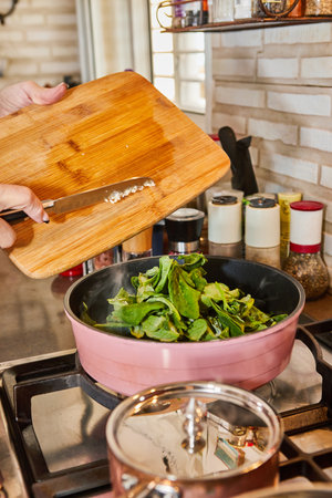 Chef is frying sorrel in frying pan in oil on gas stoveの写真素材