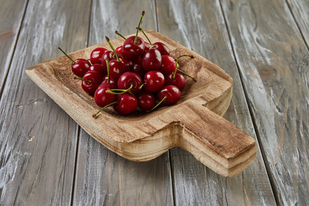 Tempting Harvest: Juicy Cherries Overflow on Wooden Scoop, Natures Sweet Bountyの写真素材