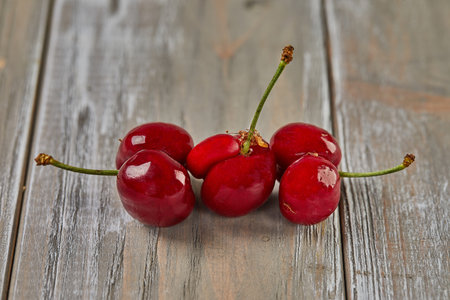 Natures Oddity: ugly, irregularly shaped cherry stands out against a rustic wooden backdropの写真素材
