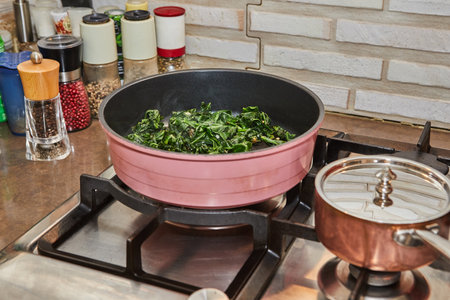 Sorrel is fried in frying pan in oil on gas stoveの写真素材
