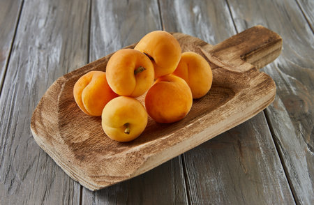Fresh apricots lie on wooden ladle on gray wooden backgroundの写真素材