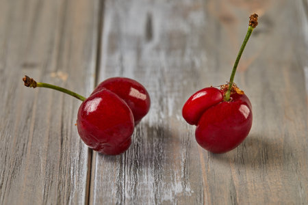Natures Oddity: ugly, irregularly shaped cherry stands out against a rustic wooden backdropの写真素材
