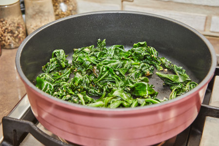 Sorrel is fried in frying pan in oil on gas stoveの写真素材