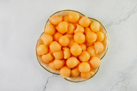 Melon balls cut with special spoon, in a bowl in the kitchen.の写真素材