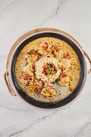 White fish fillet in wine sauce and millet porridge on plate on wooden board.の写真素材