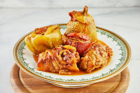 Stuffed zucchini, bell peppers and cabbage rolls on plate with an ornament on wooden stand.の写真素材