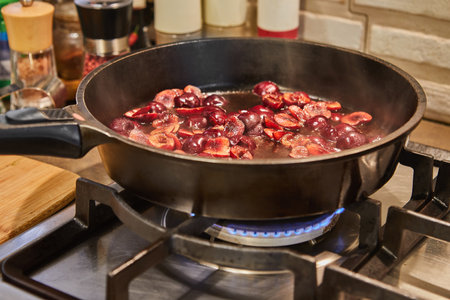 Chef fries fresh cherries in caramel syrup in frying pan on gas stove.の写真素材