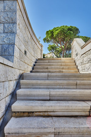 Stone staircase with stone walls and greenery against the blue sky.