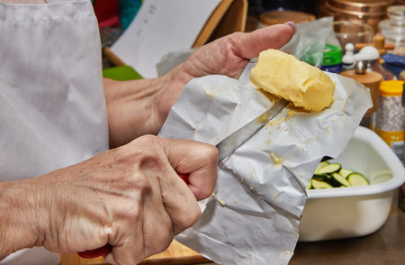 Close-up shot of a chef's hands holding a knife and taking a piece of homemade butter out of the...