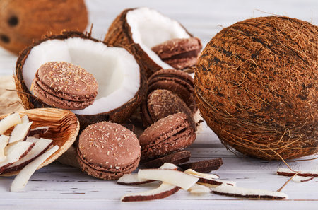 Coconut macarons with chocolate and coconut flakes on a table with a coconut in the background. The perfect image for a food blog or recipe website.の写真素材