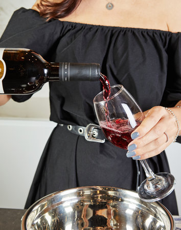 Preparing delicious mulled wine with red wine and aromatic spices in a cozy home kitchen setting.の写真素材