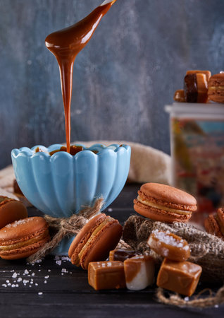 Caramel is slowly poured onto a bowl of macarons, enhancing the sweetness of the popular French dessert. The mixture of this natural food ingredient with the staple food creates a mouthwatering dishの写真素材