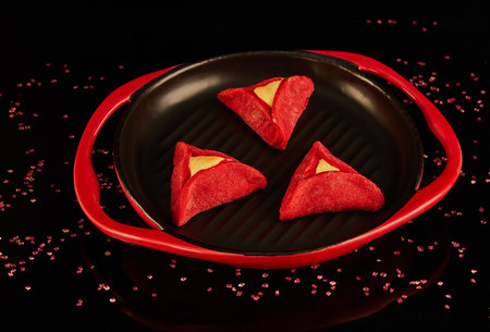 Hamans ears - hamantash are red, with Red Velvet flavor, on a black-red plate against a background with reflection.の写真素材