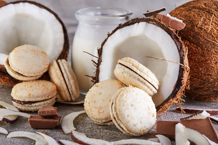 Coconut macarons with chocolate and coconut flakes on a table with a coconut in the background. The perfect image for a food blog or recipe website.の写真素材