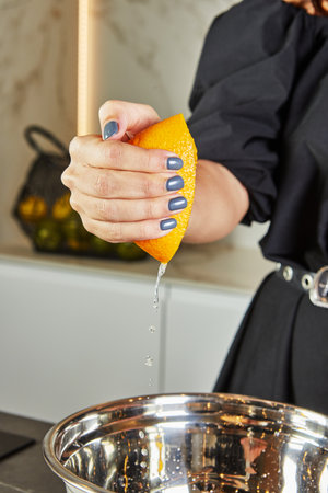 Hand squeezing orange half over a bowl on white background. Bright and vibrant colors make it ideal for recipes, healthy eating, and refreshing summer drinks. Fresh and juicy concept.の写真素材