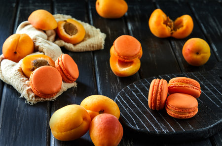 Delicious macaron with apricot flavor on a dark background with apricots. Ideal image for baking, desserts or food blog content.の写真素材