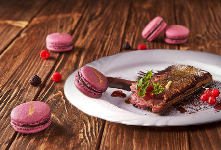 A delightful pile of purple macarons with chocolate and berries arranged on a wooden table, showing the perfect combination of sweet ingredients and baked goodsの写真素材