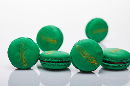 Green macarons with chocolate filling on a white background with reflection.の写真素材