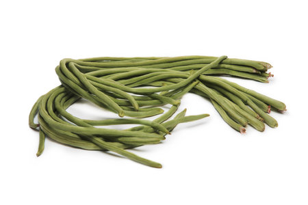 A bunch of fresh long green beans, also known as yardlong beans, arranged on a white background, highlighting their length and texture.の写真素材