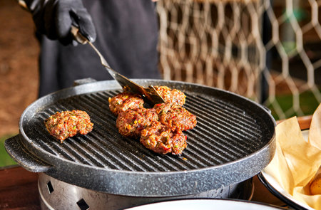 Juicy meat patties grilling on a hot iron pan, exuding delicious aroma and flavors, perfect for an outdoor cookout.の写真素材