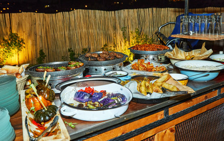 An outdoor buffet table filled with a variety of dishes, including grilled vegetables, meats, and appetizers, ready for serving.の写真素材