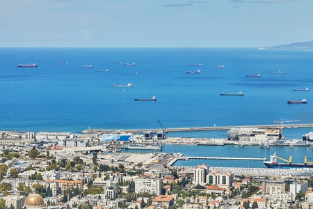 Panoramic view of Haifa, Israel with green fields, residential areas, and industrial zone under a partly cloudy blue sky.の写真素材