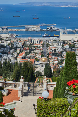 A grand stairway in Bahai Gardens leads to the shrine, framed by vibrant flowers, trimmed bushes, and a panoramic port viewの写真素材