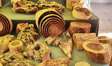 A colorful display of handcrafted wooden bowls and boxes with natural textures shown at an outdoor...